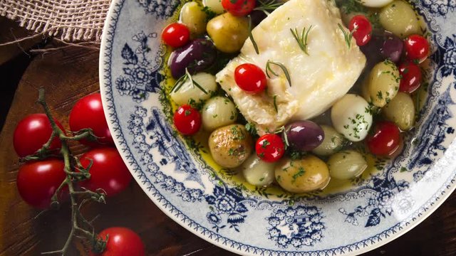 Slide shot Portuguese dish with codfish called Bacalhau do Porto in a original portuguese plate. Top view with smoke.