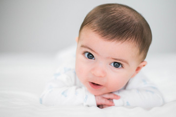 3 month old baby lying on the bed smiling with white background holding head up and aching milestones stock photo royalty free 