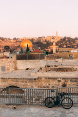Fototapeta premium View of Old Jerusalem from the Mount. View of old city from the roof, with lattice and bicycle on foreground. Sunset time over Jerusalem. Jerusalem day. Holy places. Streets of jerusalem
