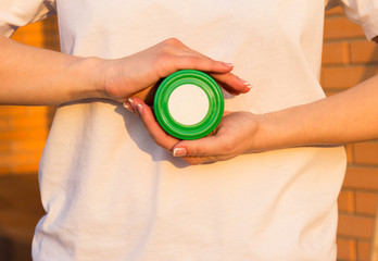 Green jar of honey or cream in women's hand. Space for your logo.