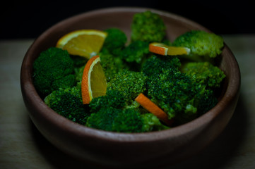 wooden plate with green broccoli vegetables, beans and a beautiful black and yellow background.