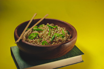 Japanese, Chinese, Asian noodles with hot green pepper on a yellow bed background and a wooden plate