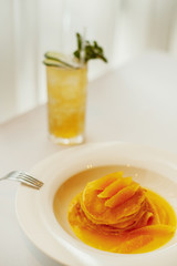 Pancakes with orange on a white plate and lemonade