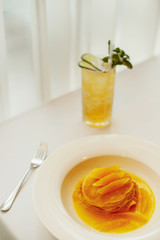 Pancakes with orange on a white plate and lemonade