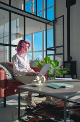 Thoughtful creative gen z hipster young woman, teen girl with pink hair using pc laptop computer...