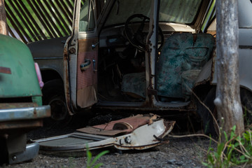 an old rusty abandoned car with its doors open