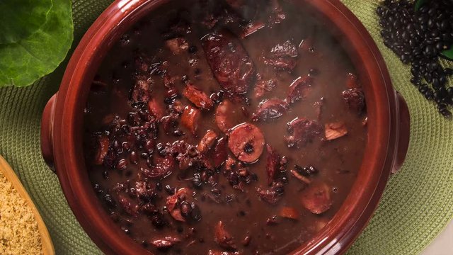 Slide shot Brazilian feijoada on the table with smoke. Top View