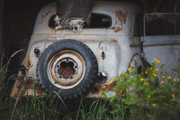 a rusty, broken-down white car with a spare wheel
