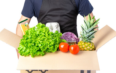 Man holding a carton box with lettuce, tomato and spaghetti, pineapple isolated on white. Delivery service, online shopping