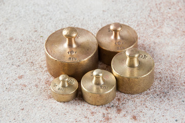 Five antique bronze weights for scales on concrete background.