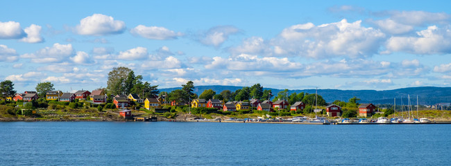 Panoramic view of Nakholmen island on Oslofjord harbor near Oslo, Norway, with marina and summer cabin houses at shoreline in early autumn