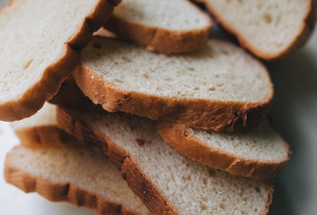 Scattered pieces of white dried bread lie on a white background. Photography, concept.
