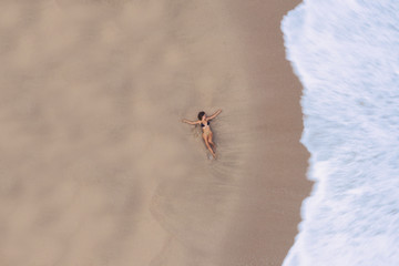 woman laying down at the beach, surrounded by waves