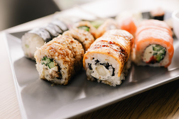 Freshly cooked sushi chef, delicious big rolls with avocado, cheese, salmon, sesame seeds 