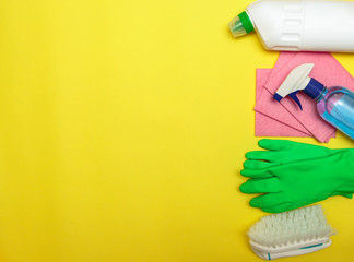 Set of cleaning and detergents, gloves and a brush on a yellow background, space for text. Cleaning. Disinfection. Flat lay.