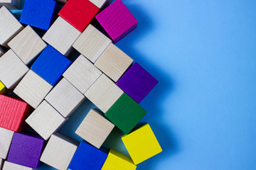 Wooden multicolor cubes on blue paper. Place for advertising. Multicolor game of wooden cubes. Multicolor composition.