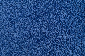 The texture of a fluffy fabric with a close-up pile. Blue Terry cloth background. Soft, plush blue material.