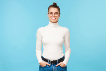 Teenage girl in white sweater and blue jeans, standing with hands in pocket, feeling confident and...