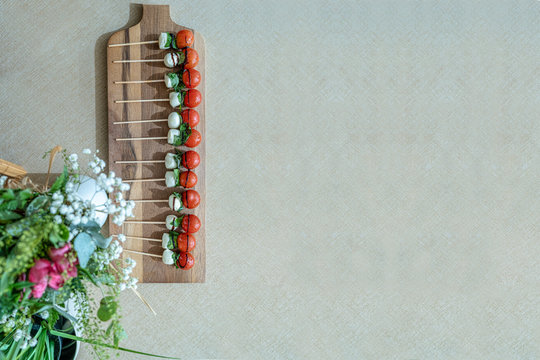 Tabla de madera con brochetas de tomate cherry y mozzarella.  Vist superior. Espacio libre para texto