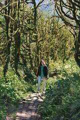 photo of a girl, walking along the trail path, through Dead boxwood forest to Mirveti Waterfall in the mountains of Georgia at sunny day, in spring.