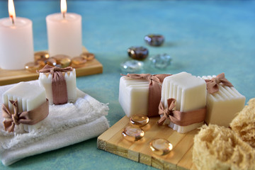 Fototapeta na wymiar Spa and relaxation concept. Bath and aromatherapy accessories in natural wood craft table, handmade soap, sea sponge, towel, lighted candles and glass gems. White, water blue, beige colors.