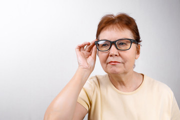 Fototapeta premium senior woman looks away with glasses on a white background in a light T-shirt. place for text, isolated