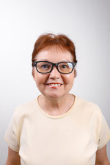 Fototapeta premium happy senior woman with glasses on a white background in a light T-shirt. place for text, isolated