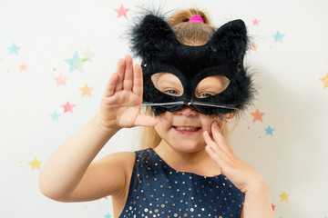 Happy Halloween 2021. Little girl child in black cat mask, carnival costume. Funny face