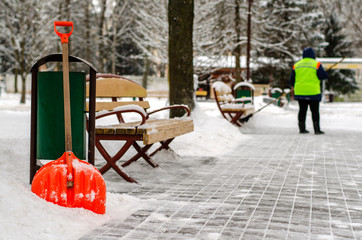 snow storm in the city. Roads and sidewalks covered with snow. Worker shovel clears snow. Bad...