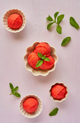 Homemade strawberry, red berry ice cream , sorbet with mint leaves on pastel pink background. Top view