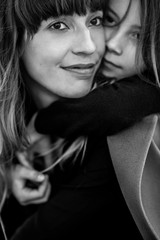 Loving mother and daughter gently hug each other on the beach at sunset, they smile and enjoy communication. Black and white photo.