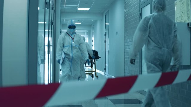 Doctors in hazmat suits walking along a hall on quarantine