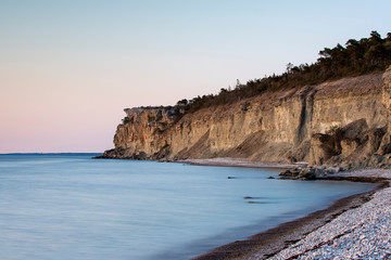 Stone beach with limestone cliff in background, Sweden