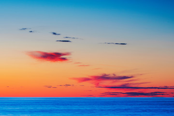 Vibrant colored summer sunset reflecting in ocean with endless horizon and deep blue ocean at island of Gotland in Sweden