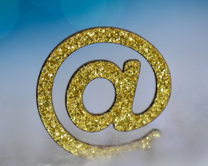 glittery gold at symbol with blue background 