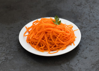 Vegetable appetizer Korean carrots and parsley on a plate on a dark background