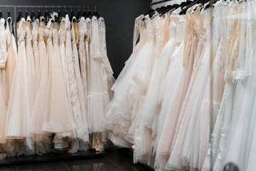 Wedding dresses made of silk chiffon, tulle and lace. Beautiful White cream bridal dress on hangers in wedding salon.