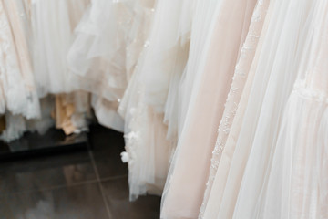 Fototapeta na wymiar Wedding dresses made of silk chiffon, tulle and lace. Beautiful White cream bridal dress on hangers in wedding salon.