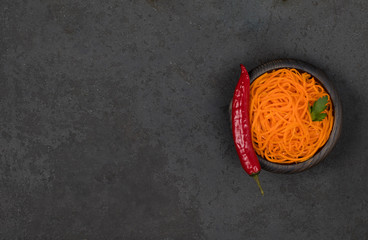 Vegetable appetizer Korean carrots with garlic and pepper and parsley in a wooden bowl on a dark background in rustic style top view copy space