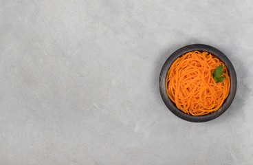 Vegetable appetizer Korean carrots in a wooden bowl on a light background in rustic style top view...