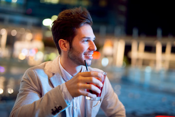 Man holding a drink at a night club outdoor