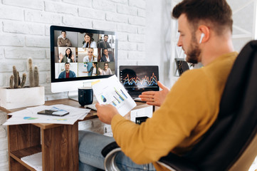 Obraz na płótnie Canvas Online business meeting. A young business man communicates by video conference with his business team about a work strategy and plan. Work from home