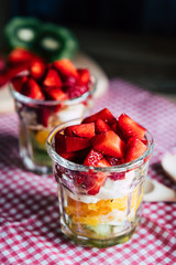 Salade de fruits colorée fait maison dans un verre transparent avec des fraises kiwis bananes et oranges 