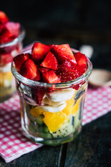 Salade de fruits colorée fait maison dans un verre transparent avec des fraises kiwis bananes et oranges 