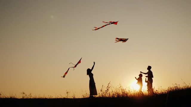 A young sam with two children plays kites at sunset in a picturesque place. Family activity outdoors