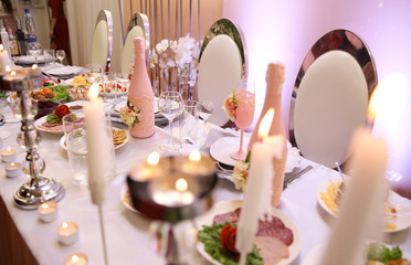Wedding table with food and candles and champagne with a flower.