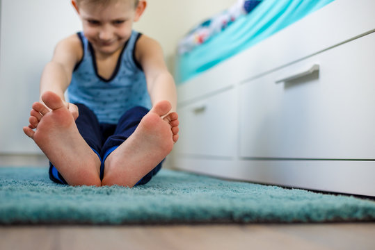 The boy trains in his room. Close-up of the feet. The concept of a healthy lifestyle. Sports at home.