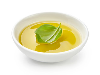 Olive or vegetable oil in white bowl. Oil with basil leaves isolated on white background.