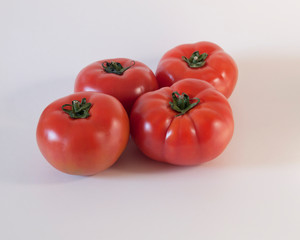 Cuatro tomates rojos maduros en un fondo blanco