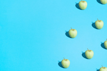 Summer abstract trendy fresh concept. green Apple pattern on bright light blue background, copy space. Minimal flat lay food texture.